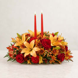 Autumn floral centerpiece with red candles, roses, and lilies