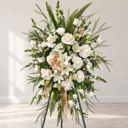 White floral standing spray on an easel with ribbon accents