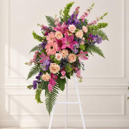 Tall floral spray with pink, peach, and purple flowers on a white easel