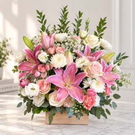 Pink lilies and roses arranged in a wooden box