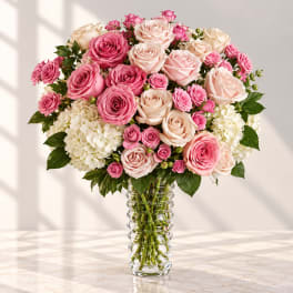 Pink and blush roses arranged in a clear glass vase