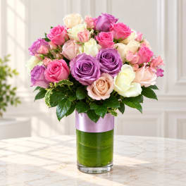 Mixed roses in pink, purple, cream, and peach in a glass vase