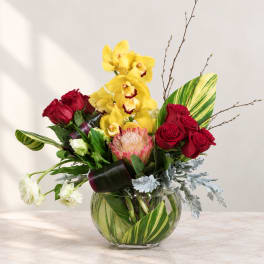 Bouquet of red roses and yellow orchids in a glass vase