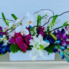 White orchids and magenta roses in a white rectangular vase