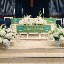 White floral altar arrangements in a church with green altar cloths