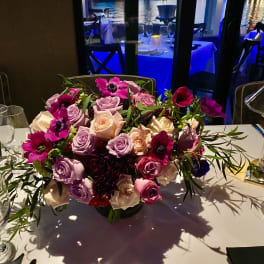 Low centerpiece of pink and lavender roses on a dining table