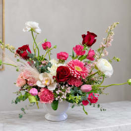 Mixed pink and red flower arrangement in a white vase