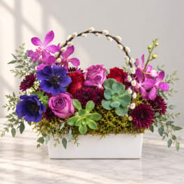 Colorful floral arrangement in a white rectangular container with roses, orchids, and succulents
