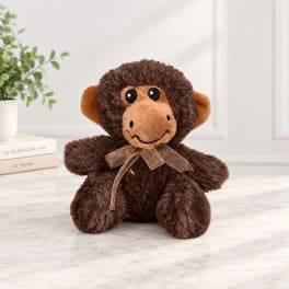 Brown plush monkey with a ribbon bow sitting on a tabletop