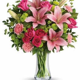 Pink lilies, roses, and carnations in a clear glass vase