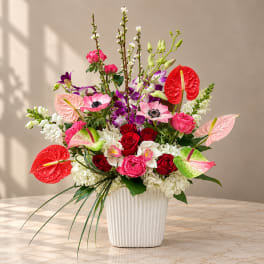 Colorful floral arrangement in a white ribbed vase with roses and orchids