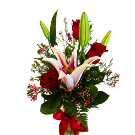Red roses and pink lilies in a glass vase with a red ribbon
