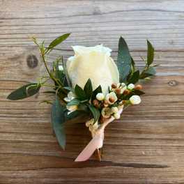White rose boutonniere with greenery and small white berries