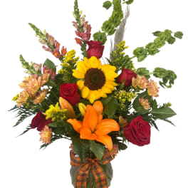 Sunflower and red rose bouquet in a glass vase with an orange ribbon