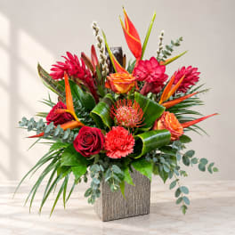 Tropical bouquet with red and orange flowers in a textured square vase