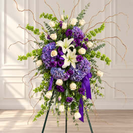 Tall floral standing spray with white lilies, cream roses, and purple blooms