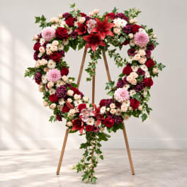 Heart-shaped floral wreath on a wooden easel with red, pink, and white flowers