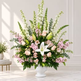Large pastel flower arrangement in a white vase with lilies and roses