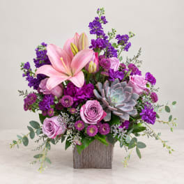 Pink lilies and roses with purple flowers in a wooden vase