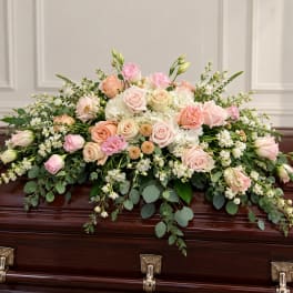 Pastel floral spray on a casket with roses and white blooms
