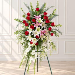 Standing floral spray with red roses and white lilies on a metal easel