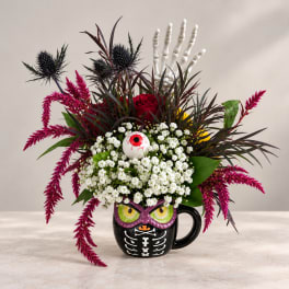 Halloween floral arrangement in a black skeleton mug with an eyeball topper
