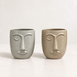 Two face-shaped ceramic planters in gray and beige