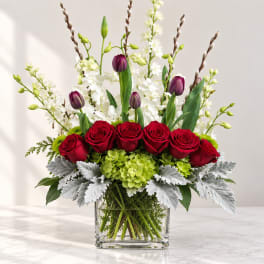 Red roses and purple tulips in a clear square vase