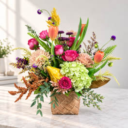 Colorful flower arrangement in a woven basket with roses, tulips, and hydrangea