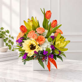 Colorful bouquet of tulips, roses, and sunflowers in a white vase