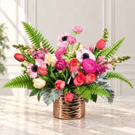 Pink and red mixed flower arrangement in a copper vase