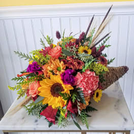 Colorful bouquet with sunflowers, roses, and carnations in a woven cone wrap