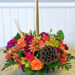 Colorful floral centerpiece with a tall gold taper candle