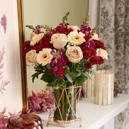 Bouquet of cream roses, red mums, and purple flowers in a glass vase