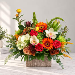 Colorful mixed flower arrangement in a textured rectangular vase