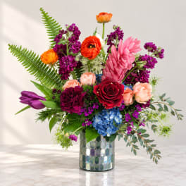 Colorful mixed bouquet in a mirrored vase with roses and tulips