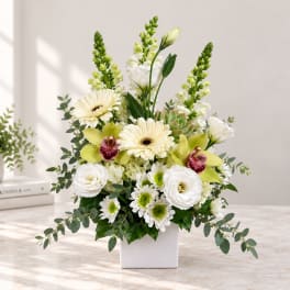 White and green floral arrangement in a square white vase
