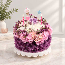 Round floral cake with purple and pink flowers and birthday candles