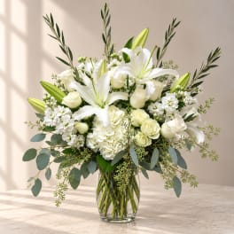 White lilies and roses arranged in a clear glass vase