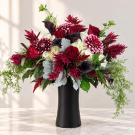 Red and white floral arrangement in a black vase
