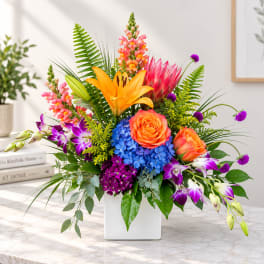 Colorful mixed flower arrangement in a white square vase