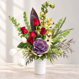 Mixed bouquet in a white vase with red roses, purple cabbage, white tulips, and orchids