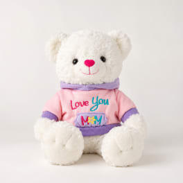 White teddy bear in a pink and purple shirt with "Love You Mom" text