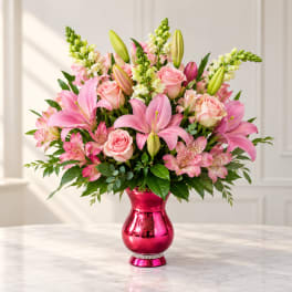 Pink lilies and roses arranged in a shiny pink vase