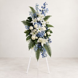 Tall white and blue floral standing spray on a white easel