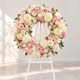 Pink and cream floral wreath on a white easel