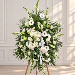 White floral standing spray with lilies, roses, and daisies on an easel