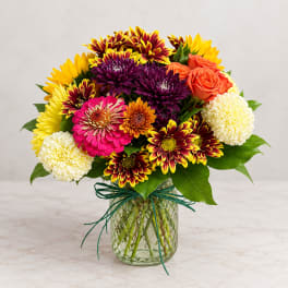 Colorful mixed bouquet in a glass vase with chrysanthemums, roses, and carnations