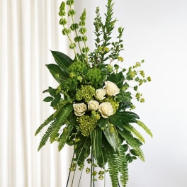 Tall floral arrangement with white roses and lush green foliage on a stand