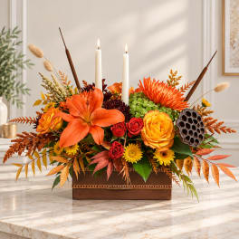 Autumn floral arrangement with orange lilies, roses, and candles in a wooden box